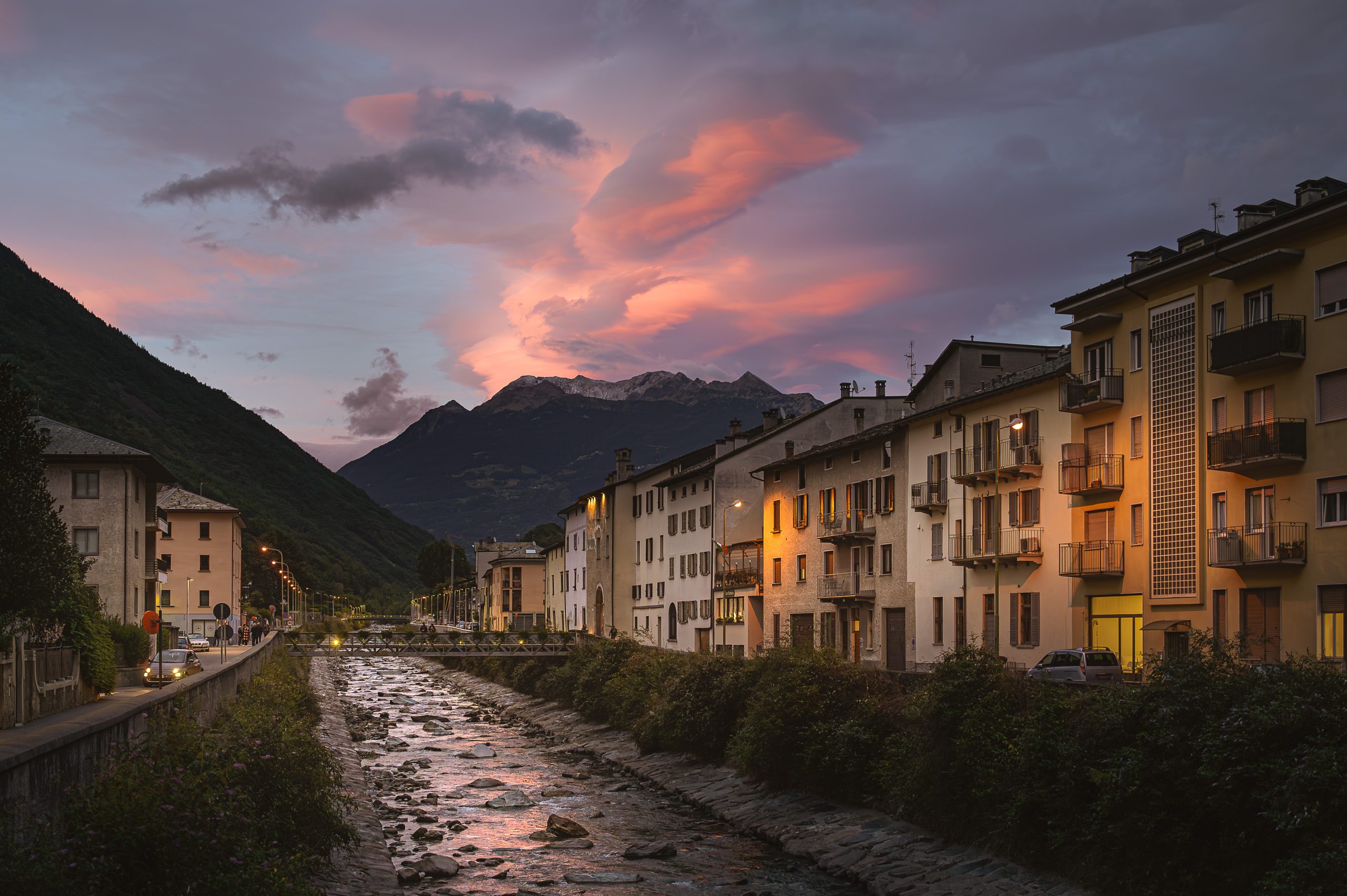 Centro urbano lungo il fiume al tramonto con montagne sullo sfondo