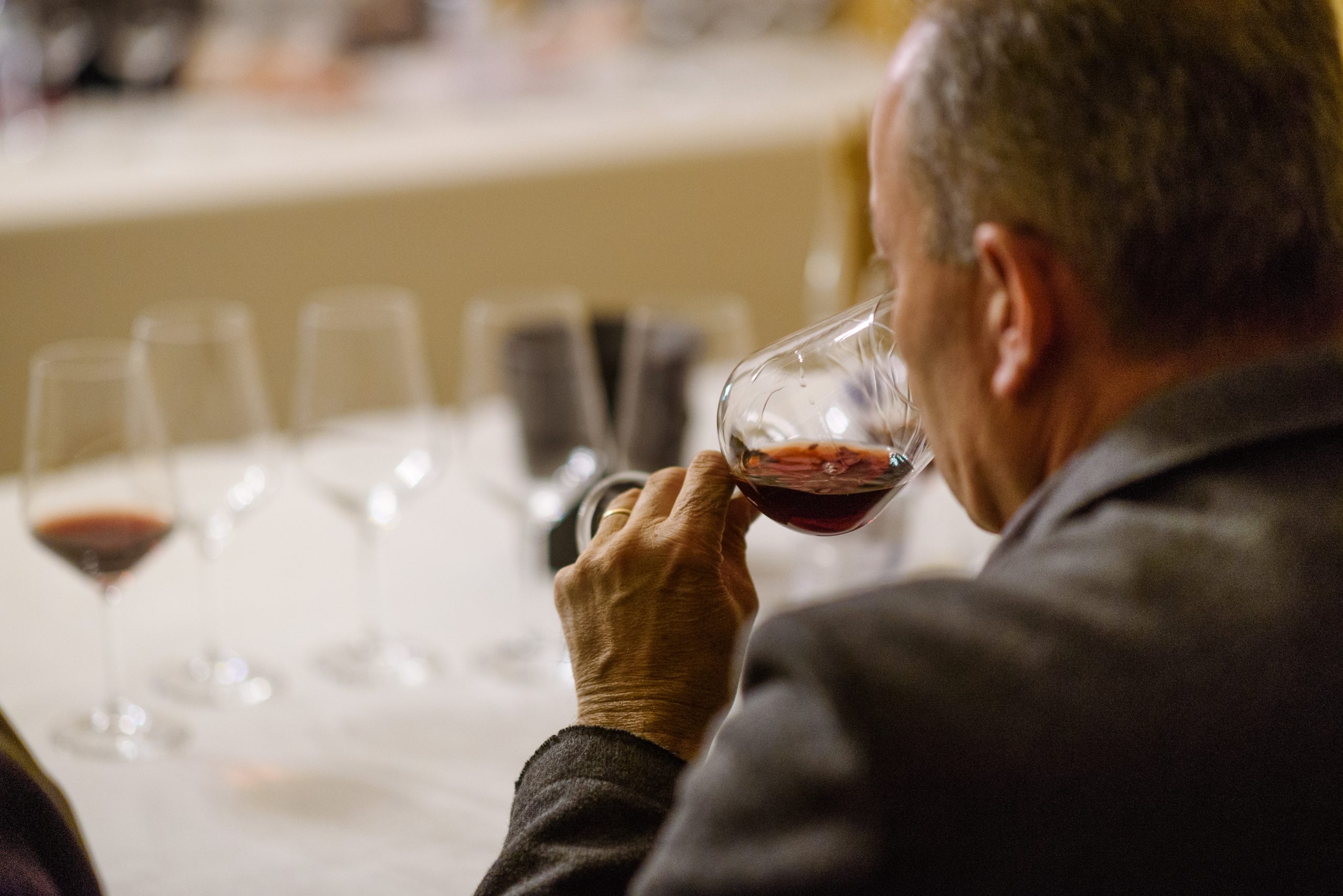 Degustazione di vino rosso con calice tenuto alla bocca durante assaggio