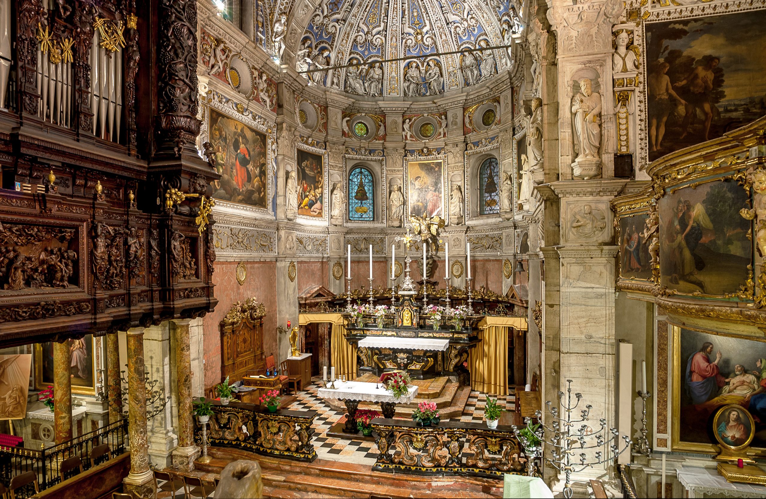 Intérieur d'une église baroque avec un maître-autel richement décoré, des fresques, des statues et une coupole ornée