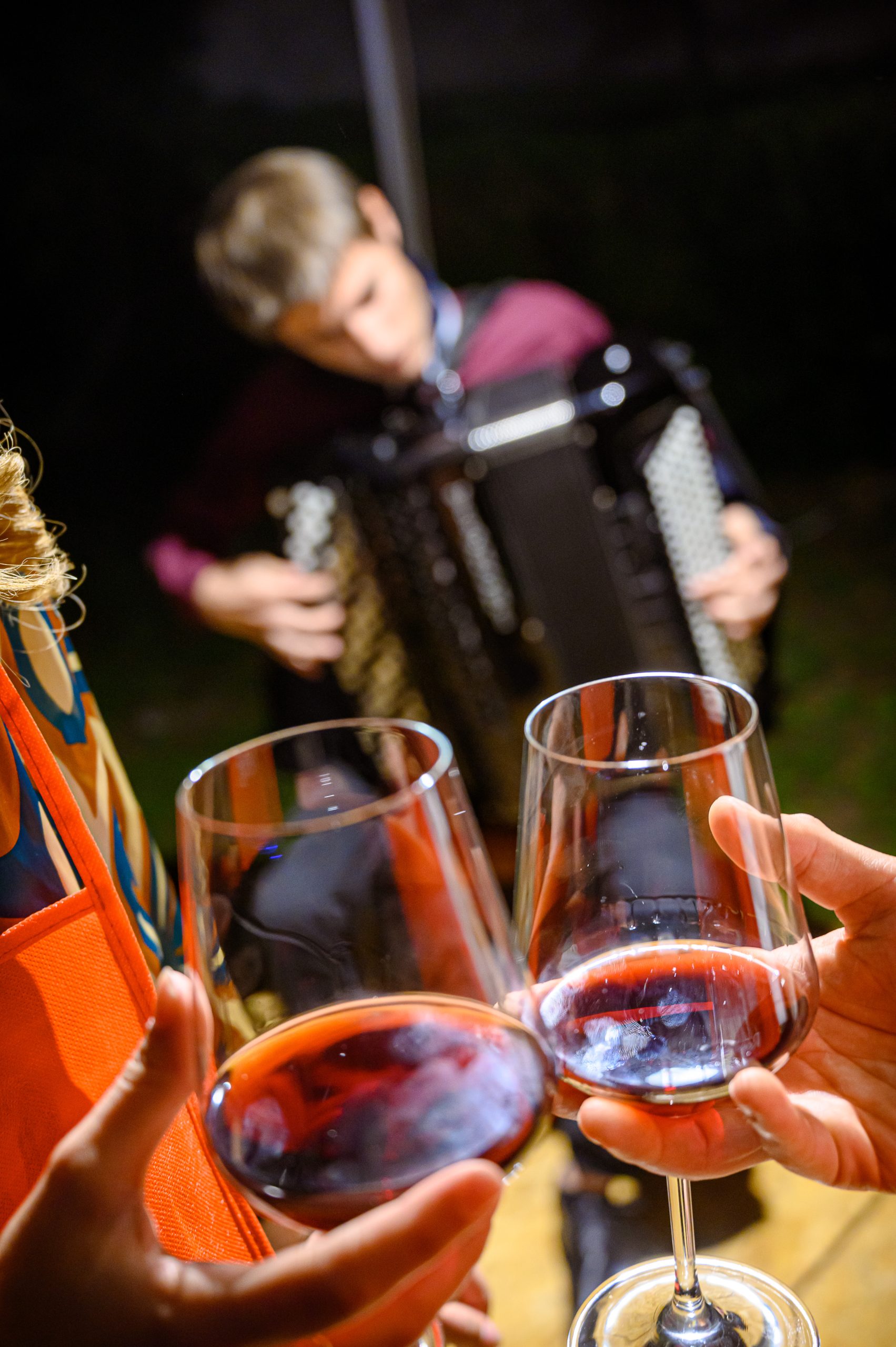 Brindisi con bicchieri di vino rosso durante una serata con musica dal vivo