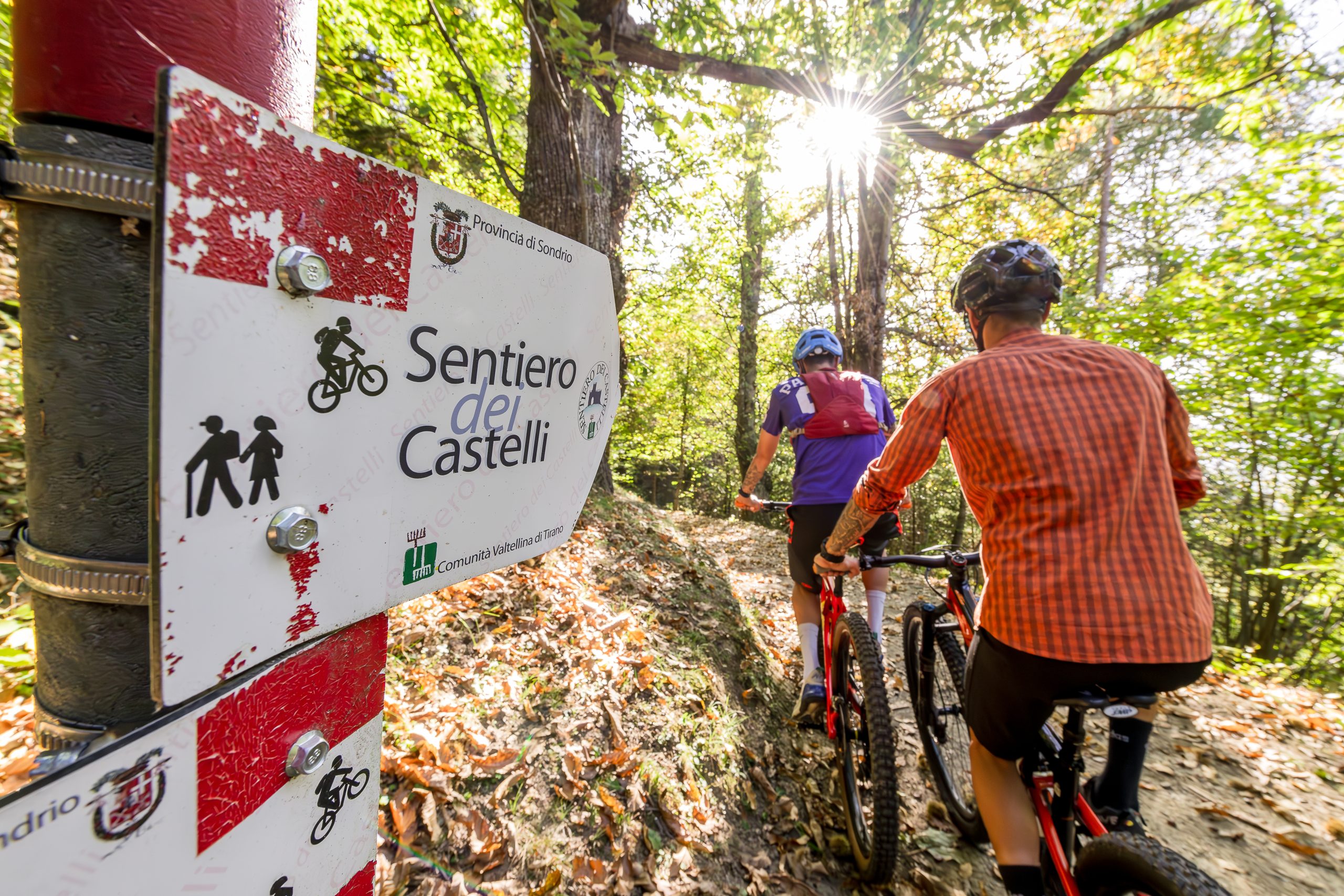 Ciclisti su sentiero boschivo con segnaletica Sentiero dei Castelli