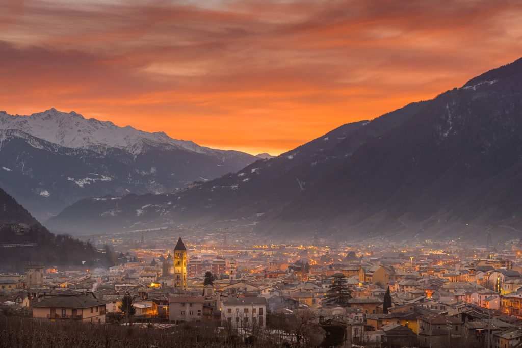 Città alpina al tramonto con montagne sullo sfondo