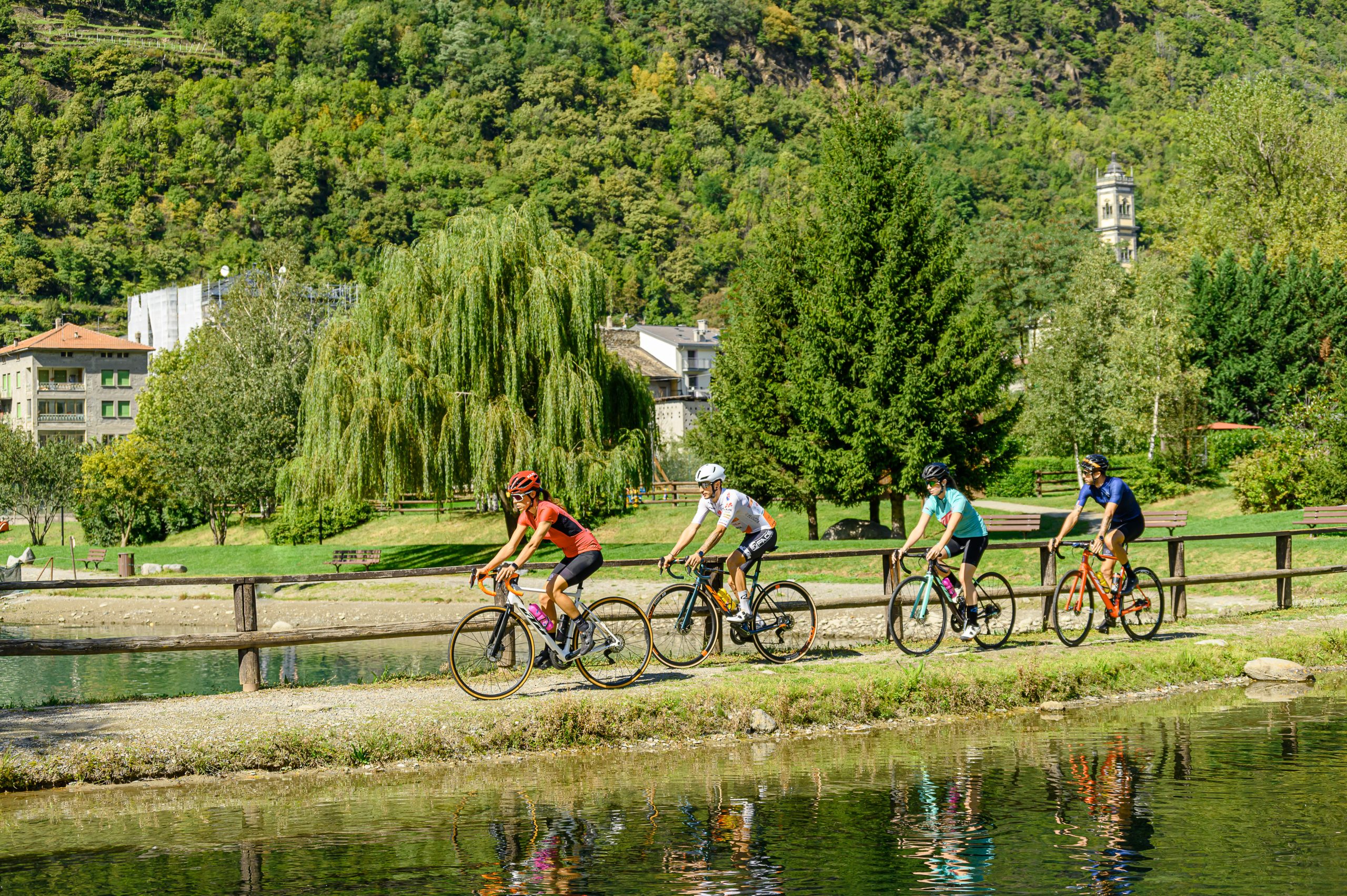 Gruppo di ciclisti su percorso ciclabile lungo un corso d’acqua