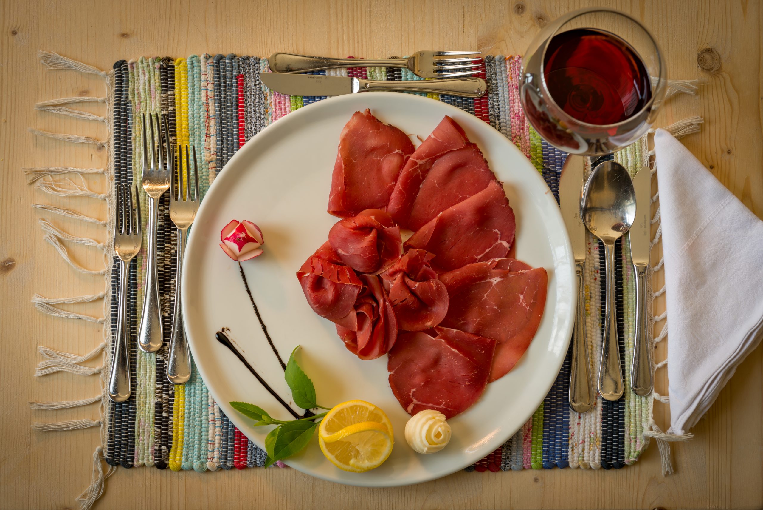 Bresaola della Valtellina servita con limone e vino rosso