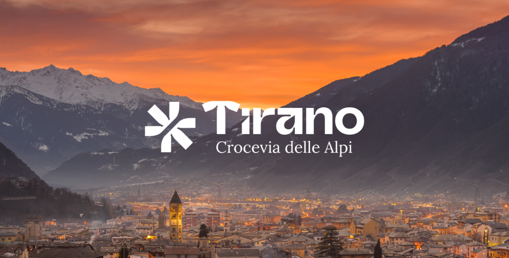 Veduta panoramica di Tirano al tramonto con montagne alpine e cielo arancione