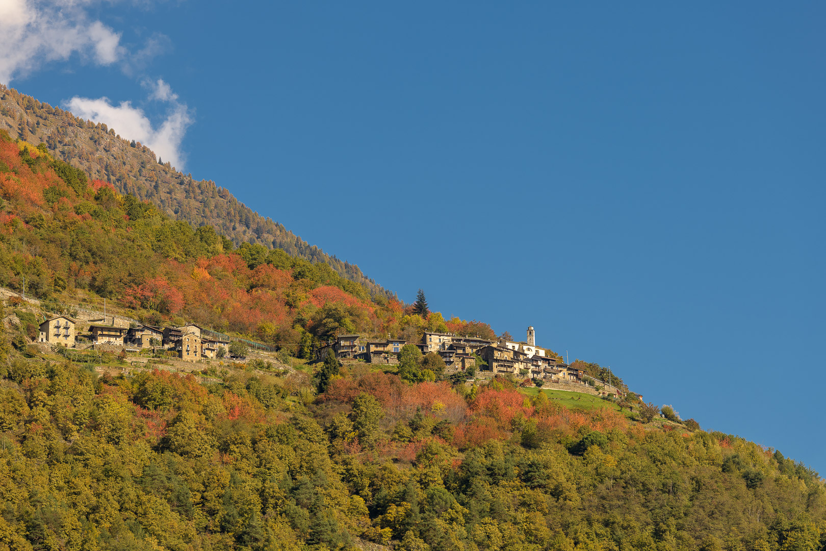 Borgo di montagna su pendio boscoso con colori autunnali