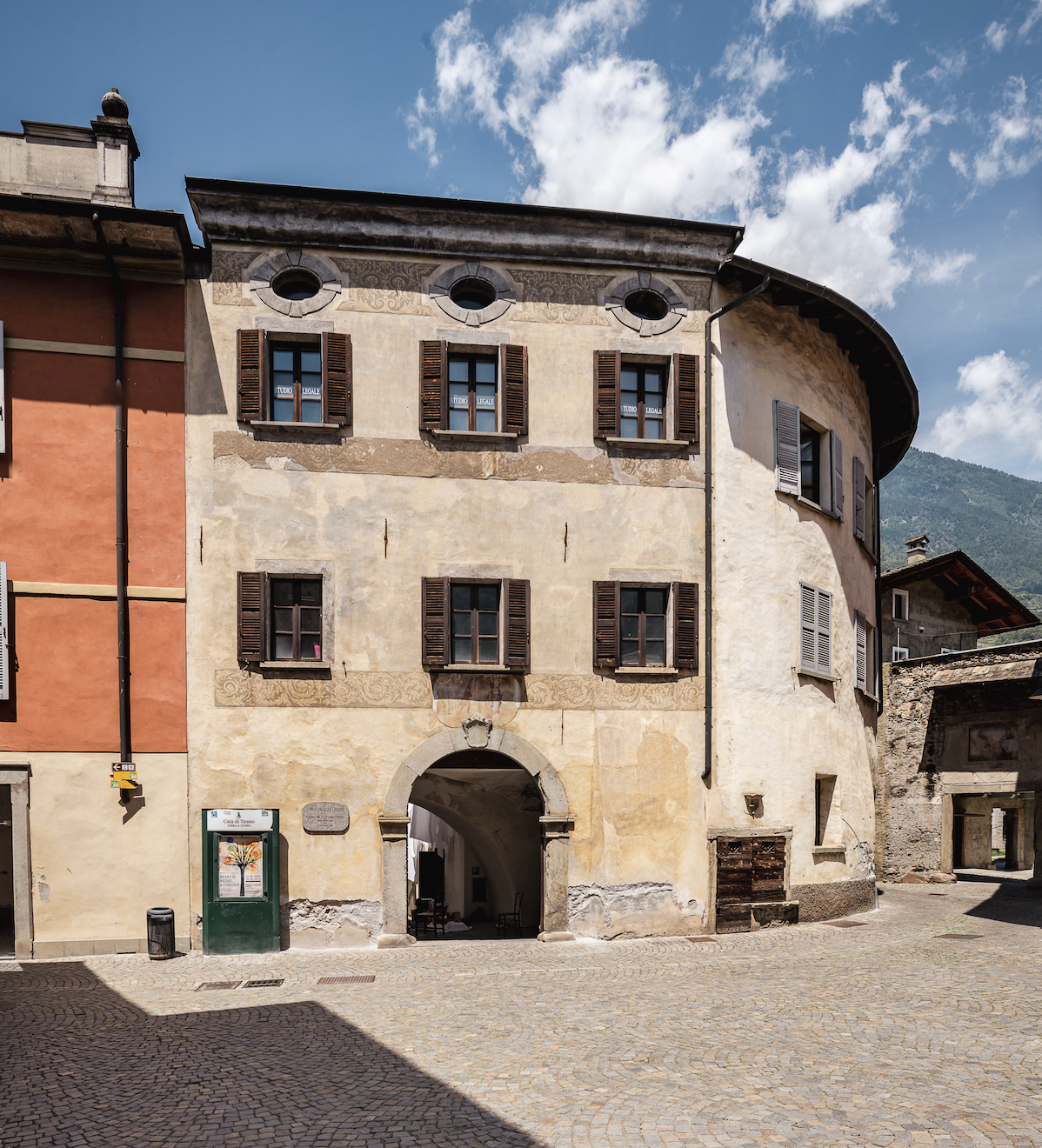 Edificio storico con portico ad arco e finestre con persiane in centro storico
